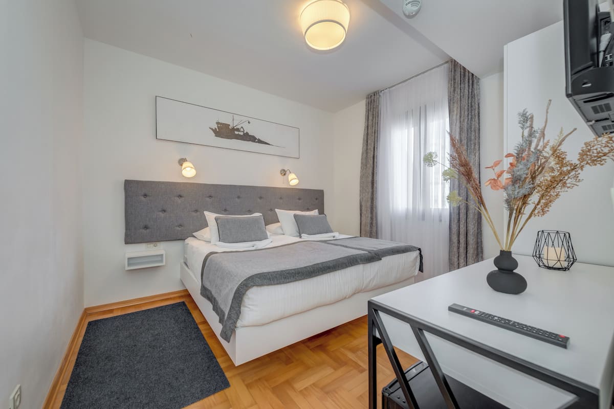 A neatly arranged bedroom with a bed, bedside tables, a desk, and a chair.