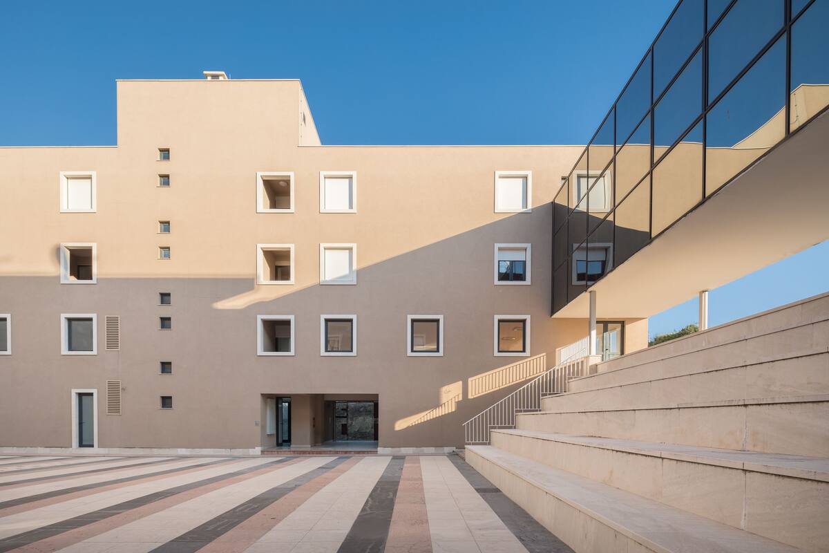 A modern building with a flat facade, multiple windows, and a central entrance.