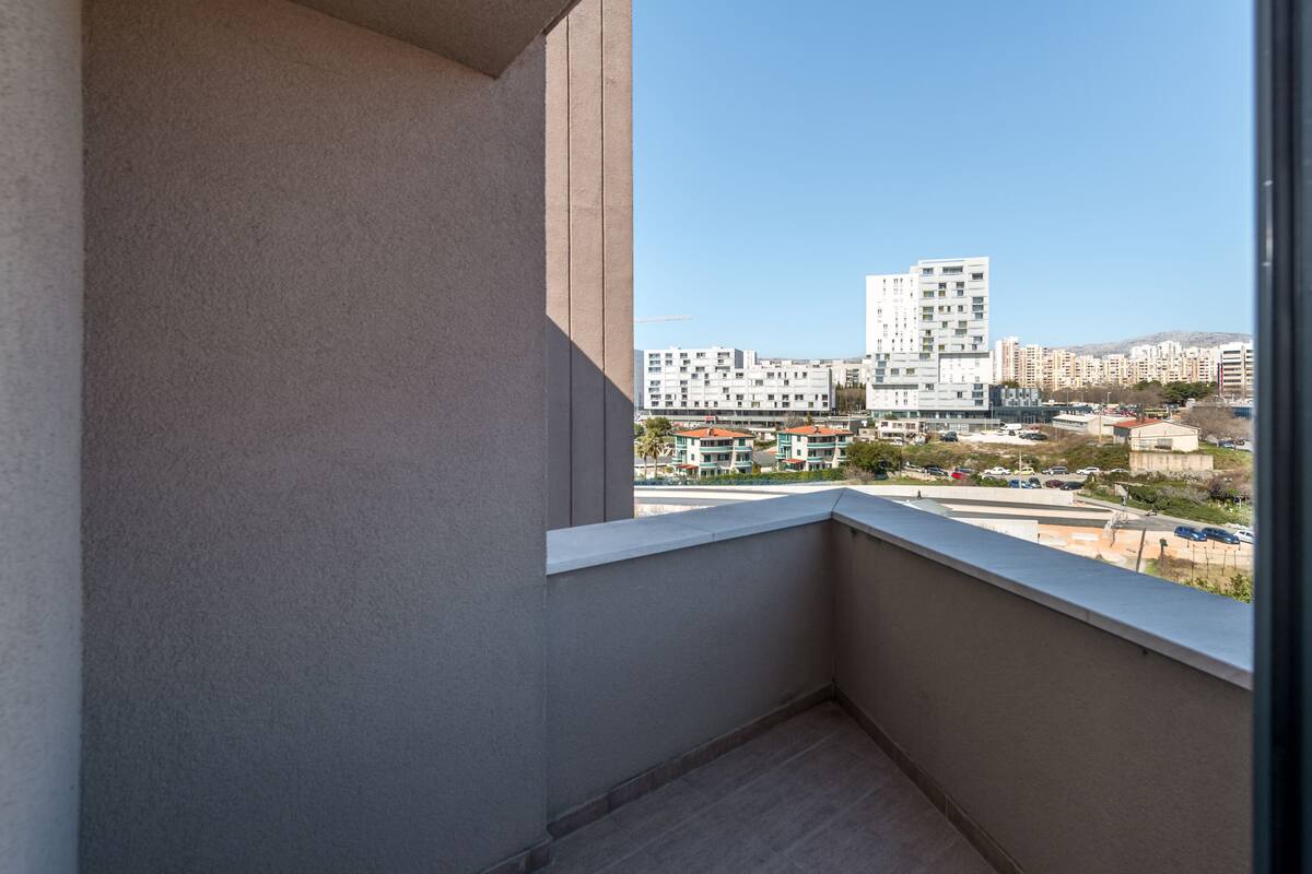 A balcony with a view of a cityscape, including modern buildings and a clear sky.