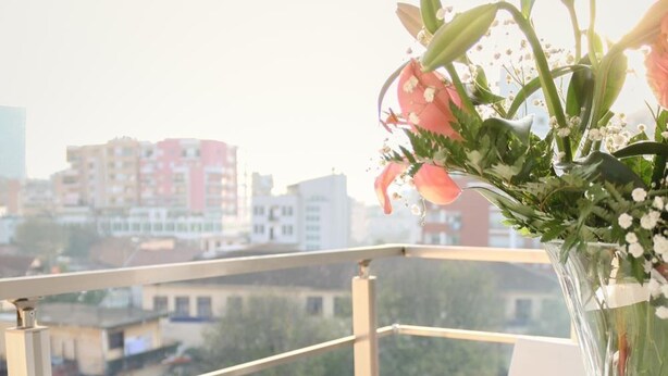 Una mesa con un croissant, un tazón de sopa y una taza de té en un balcón con vistas a la ciudad.