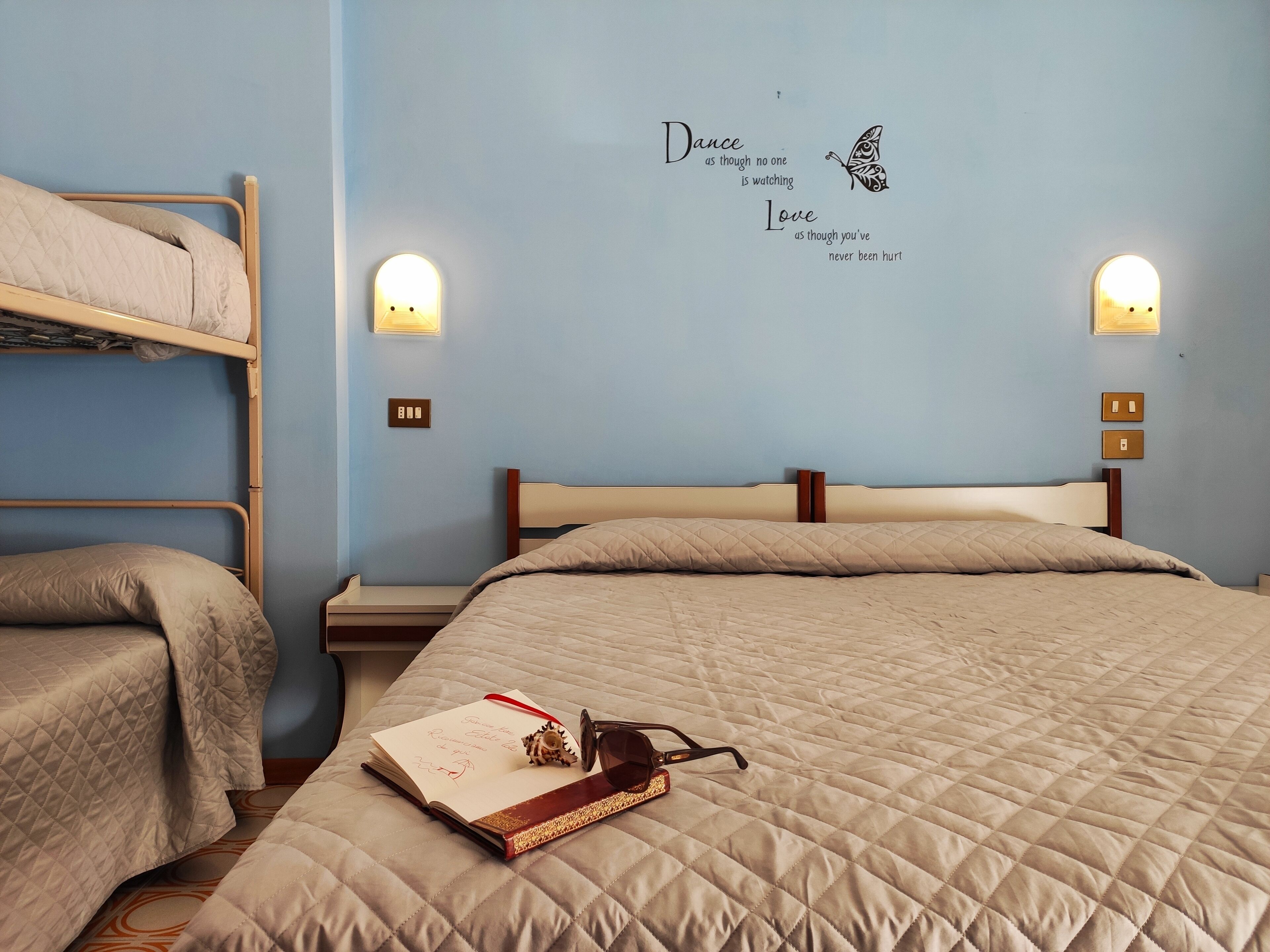 Un dormitorio con literas, una cama individual y una pared con citas motivacionales.