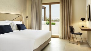A modern hotel room with a large bed, a desk, and a view of the outdoors. - Aegon Mykonos, Autograph Collection (Mykonos)