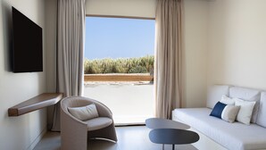 A modern room with a sofa, a chair, a small table, and a TV mounted on the wall. - Aegon Mykonos, Autograph Collection (Mykonos)