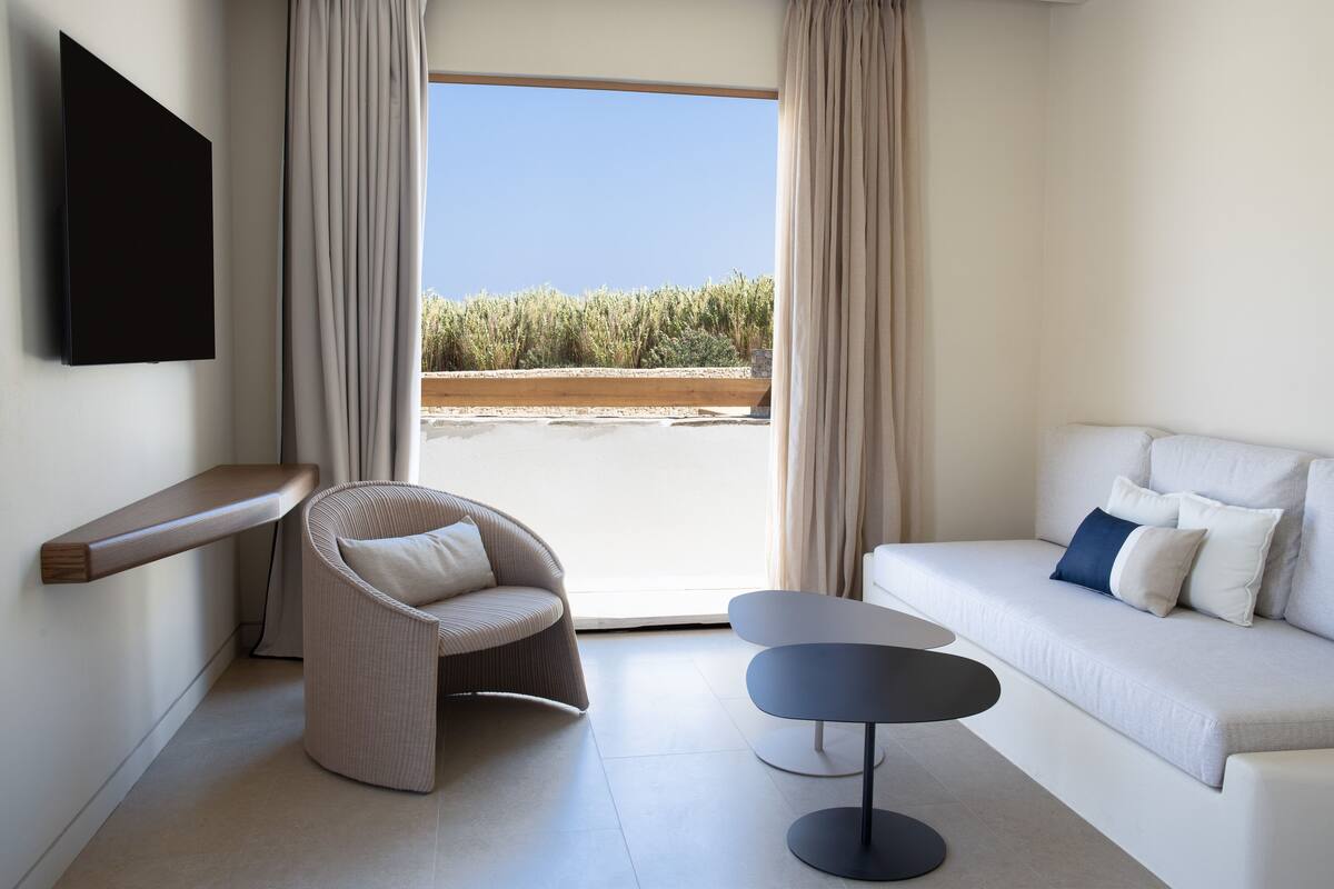 A modern room with a sofa, a chair, a small table, and a TV mounted on the wall.