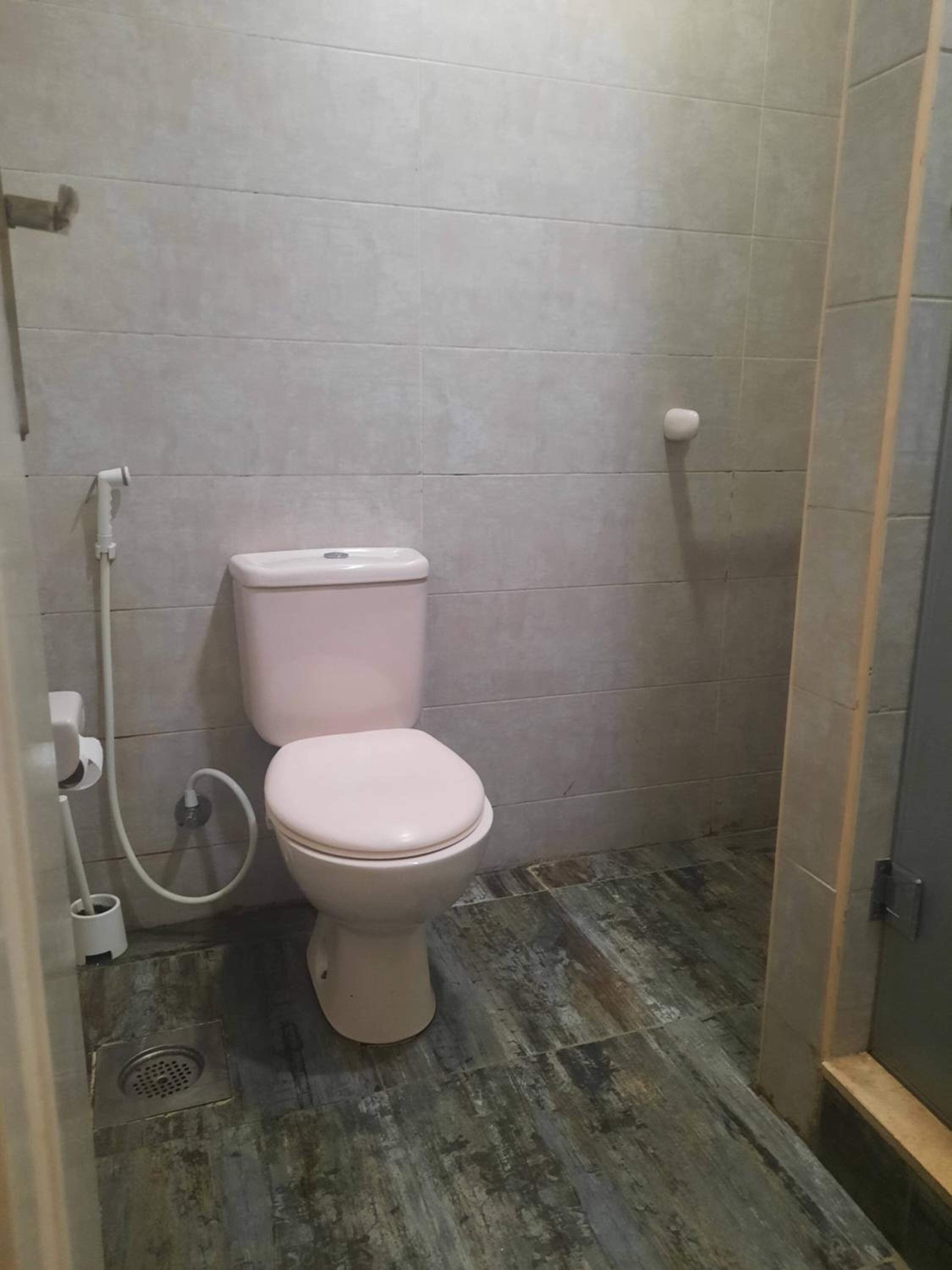 A small bathroom with a toilet, a shower, and a tiled floor.