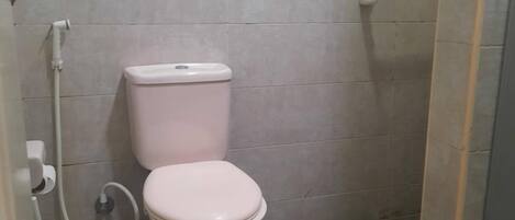 A small bathroom with a toilet, a shower, and a tiled floor.