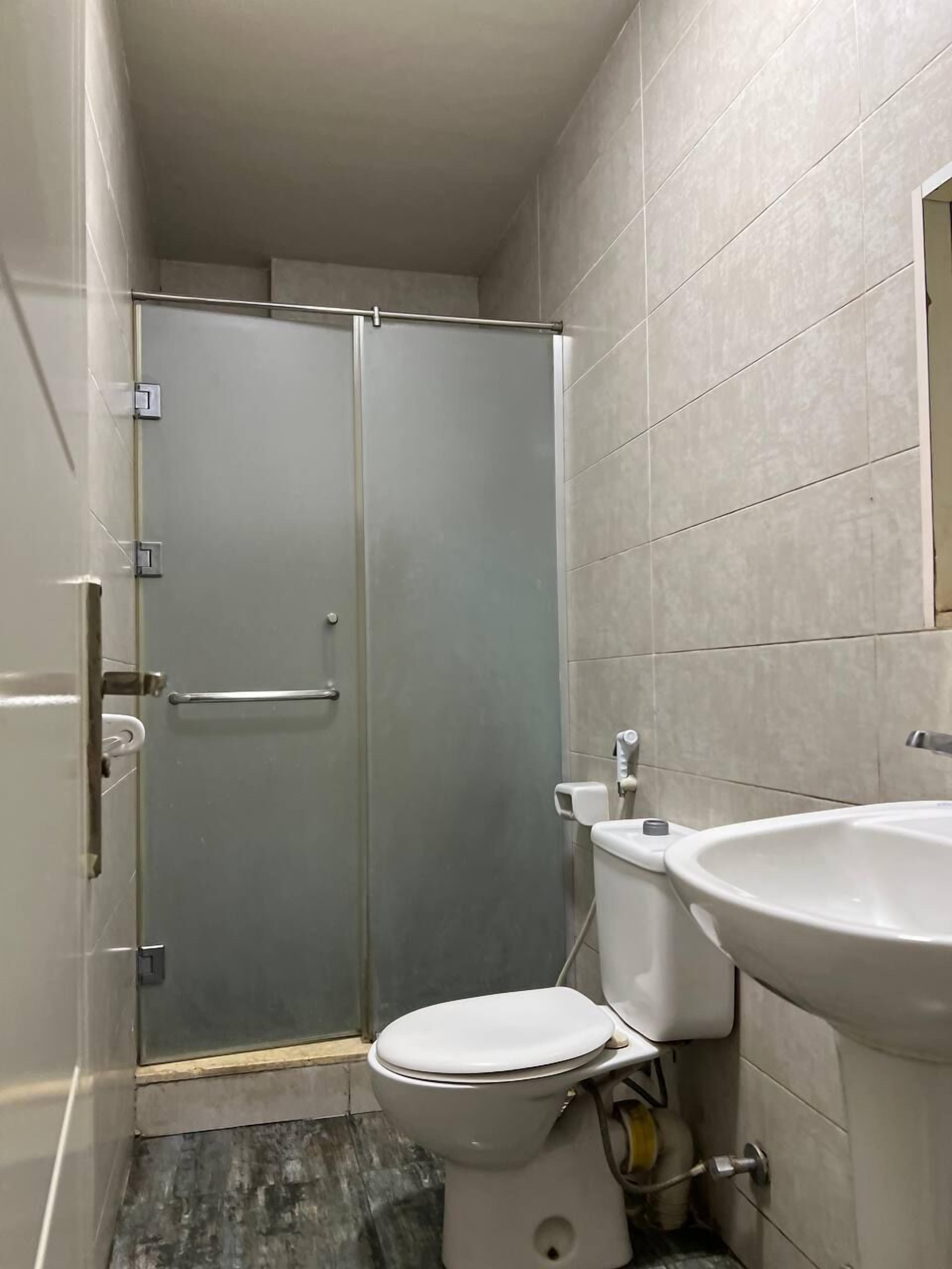 A bathroom with a toilet, sink, and glass shower enclosure.