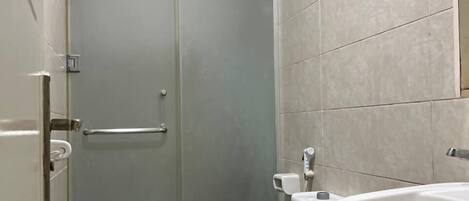 A bathroom with a toilet, sink, and glass shower enclosure.