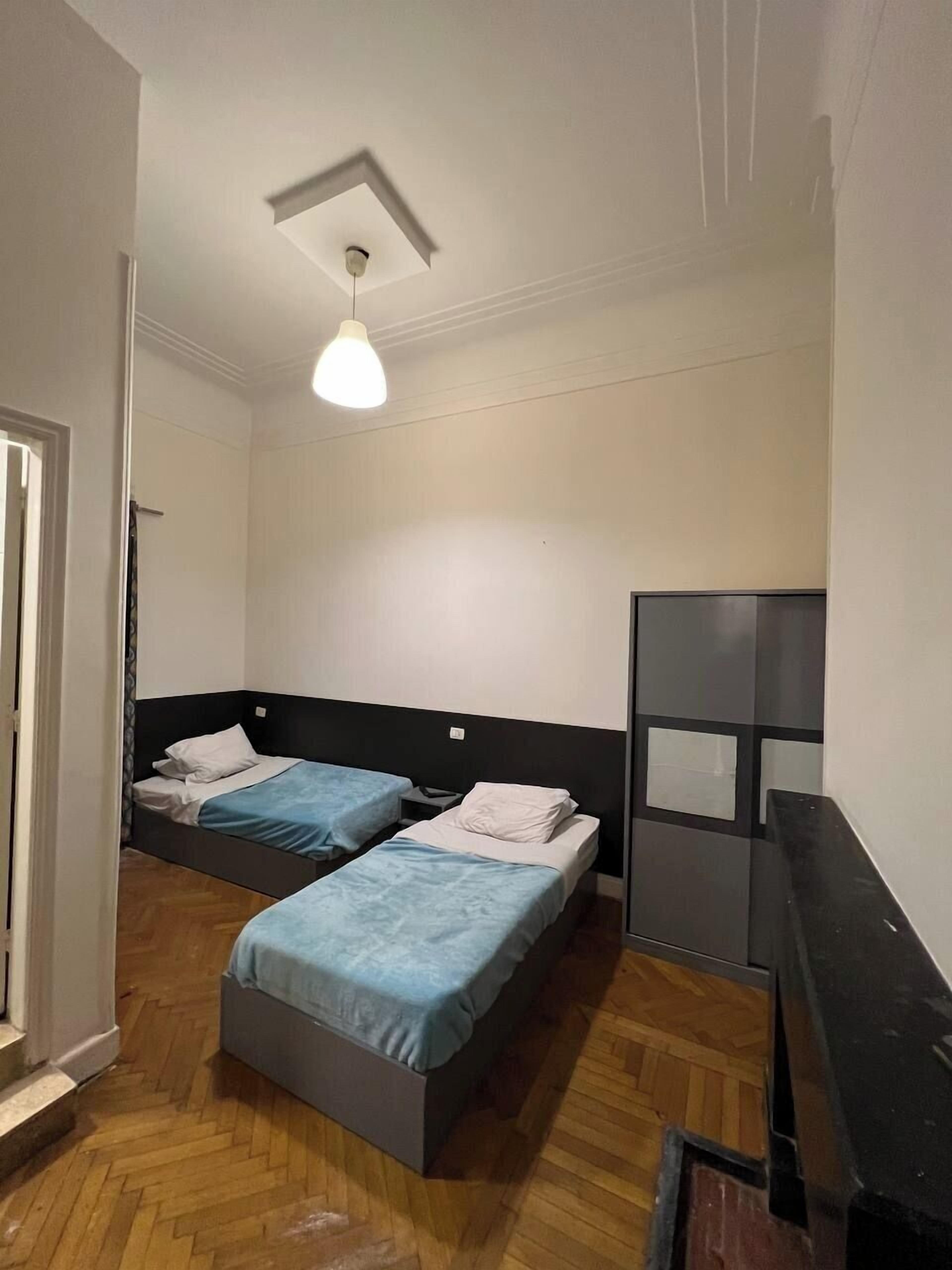 Habitació amb dos llits, una làmpada al sostre i un mirall.
