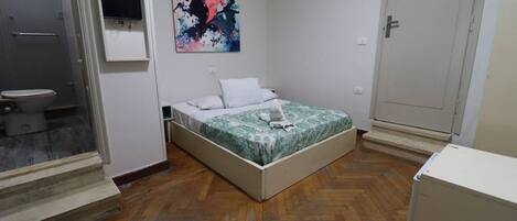 A bedroom with a bed, a bathroom with a toilet, and a door.
