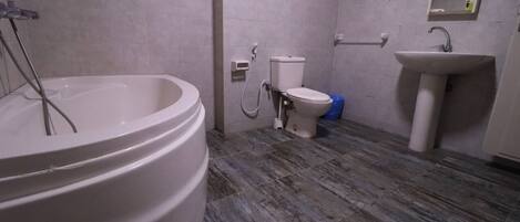 A bathroom with a large bathtub, toilet, and sink.