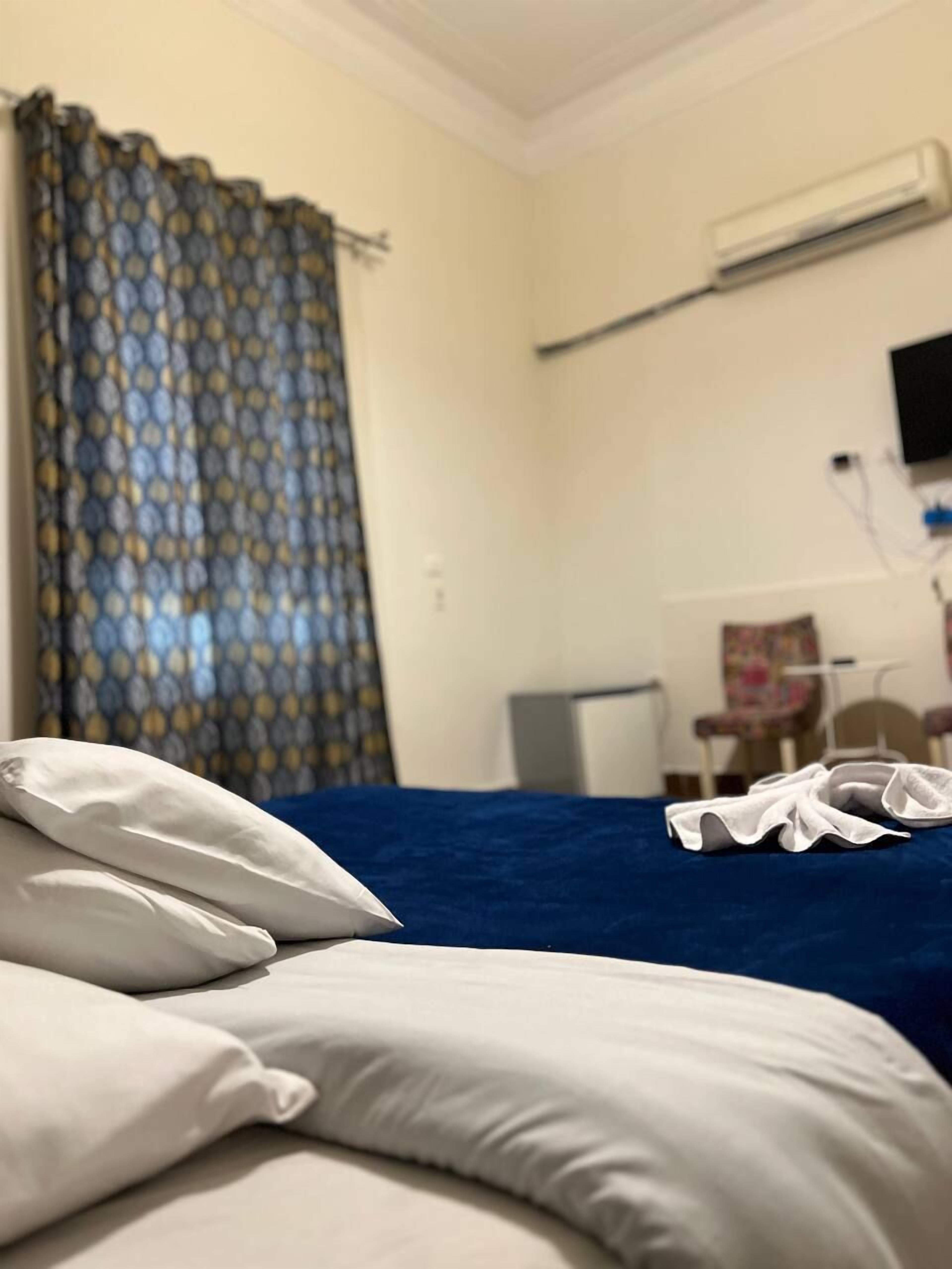 A hotel room with a bed, a TV mounted on the wall, and a window with curtains.