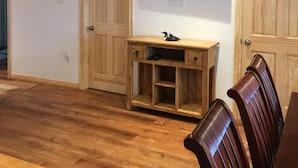 A room with wooden flooring, a TV mounted on the wall, and a wooden bench. - Loon Lodge - Golden Lake (Cottage & Bunkie -Sleeps 8 ) (Killaloe)