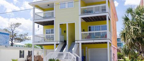 A two-story residential building with a balcony on the second floor, a front garage, and a staircase leading to the entrance.