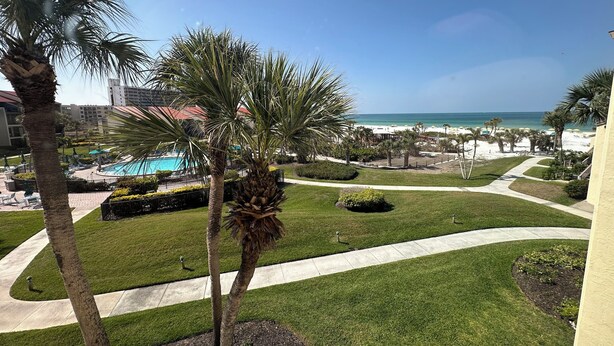 A resort with a pool, palm trees, and a view of the beach.
