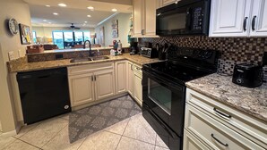 A modern kitchen with white cabinets, a black stove, and a microwave.
