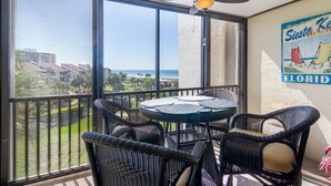A balcony with wicker furniture, a ceiling fan, and a view of the ocean.