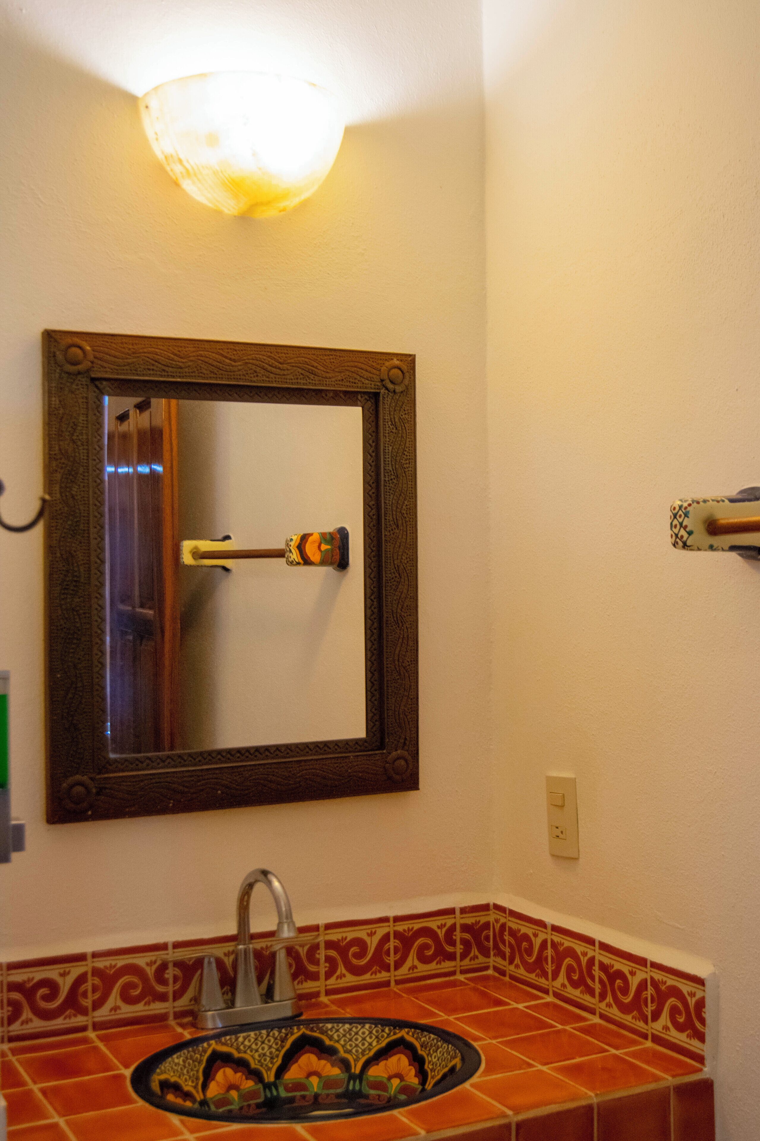 A bathroom with a mirror, sink, and decorative tiles.
