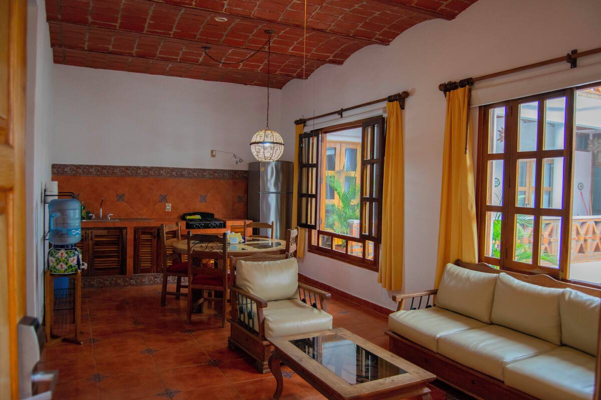 Una sala de estar con sofá, una mesa de centro y un comedor con sillas y una mesa.
