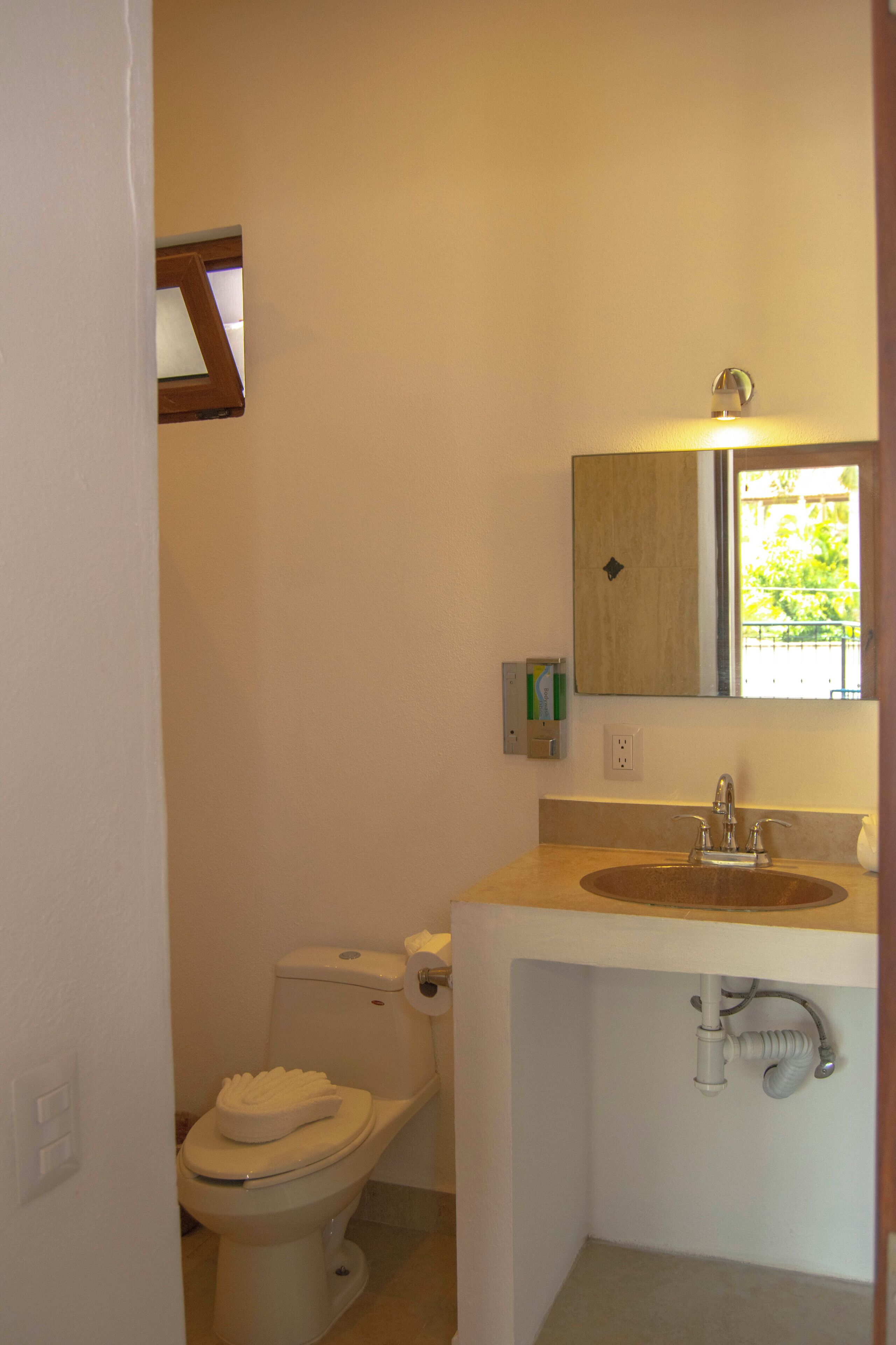 Un baño pequeño con inodoro, lavamanos y espejo.
