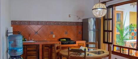 A kitchen with a water dispenser, stove, and dining table with chairs.