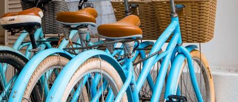 Una hilera de bicicletas antiguas con canastas de mimbre, estacionadas junto a una pared.