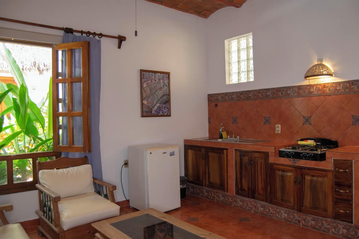 Una cocina compacta con armarios de madera, estufa integrada y un refrigerador pequeño.