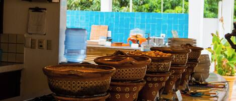 A kitchen counter with terracotta pots and utensils, a water dispenser, and a blue tiled backsplash.