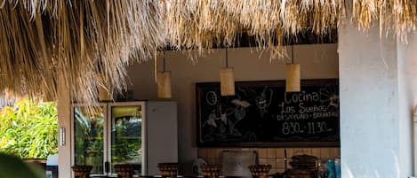 Un restaurant doté d’un toit de chaume, de tables en plein air et d’un menu écrit à la craie.
