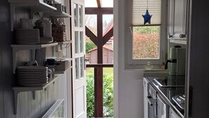 A narrow kitchen with white cabinets, a blue patterned rug, and a star decoration on the window. - Holiday house at Wittensee (approx. 2 minutes walk to the lake) with small Rowing boat, from April 2019 (Bünsdorf)