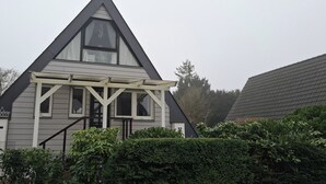 A two-story house with a gabled roof, a dormer window, and a covered porch. - Holiday house at Wittensee (approx. 2 minutes walk to the lake) with small Rowing boat, from April 2019 (Bünsdorf)