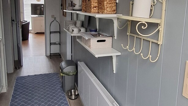 A narrow hallway with a blue patterned rug, white shelves with various kitchen items, and a radiator. - Holiday house at Wittensee (approx. 2 minutes walk to the lake) with small Rowing boat, from April 2019 (Bünsdorf)