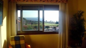 A room with a large window overlooking a scenic landscape, a chair with a plaid cover, and a potted plant. - Apartamentos Mirador de Ons for 2 people (Sanxenxo)