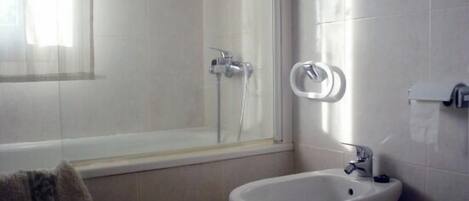 A bathroom with a bathtub, a toilet, and a bidet.