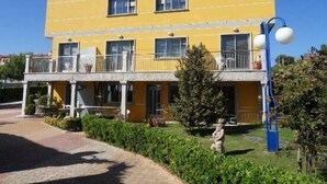 A two-story yellow building with a balcony, a small garden, and a statue. - Apartamentos Mirador de Ons for 2 people (Sanxenxo)