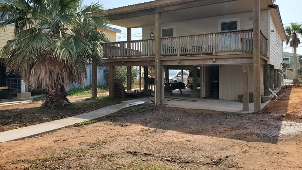 Une maison à deux étages avec un balcon, un garage et un palmier dans la cour.