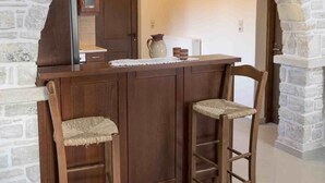 Una cocina con un arco de piedra, taburetes de madera y una encimera con cafetera.