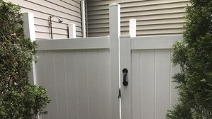 A white wooden fence with a black handle, flanked by greenery. - Newly Renovated and Private Hamptons Home (Westhampton Beach)