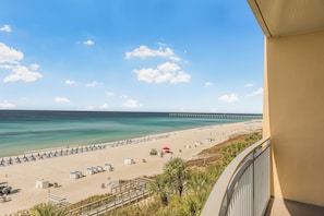 A beach view with a pier, beach umbrellas, and lounge chairs.