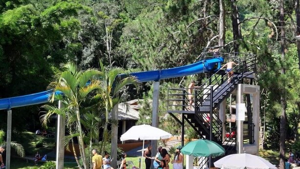 Ein Poolbereich mit Wasserrutsche, Liegestühlen und Sonnenschirmen.
