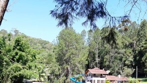 Ein Park mit Spielplatz, ein Gebäude mit rotem Dach und einer Rasenfläche.