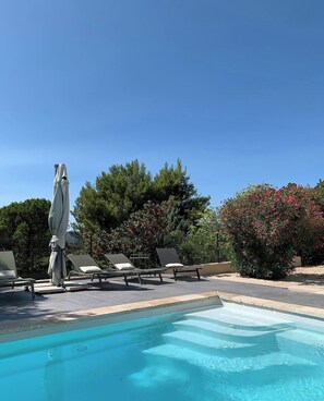 A swimming pool with lounge chairs and a covered umbrella.