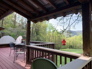 Enjoy a serene view of the lush landscape from this outdoor deck, featuring a table, chairs, and a bench.