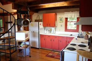 Kitchen with central island, stove, and sink, featuring cabinetry and a metal rack.
