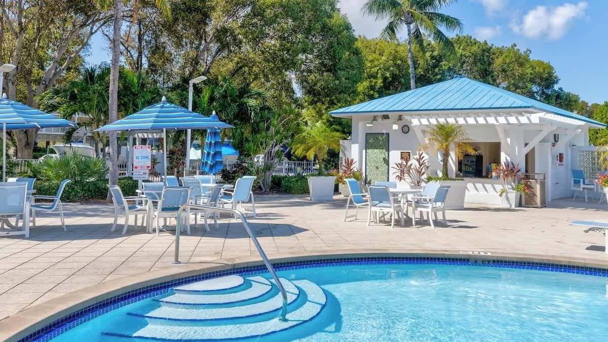 Un espace piscine équipé de chaises longues, de parasols et d’un coin salon abrité.