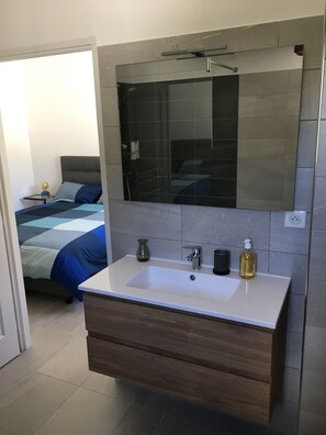 A modern bathroom with a large mirror, a white sink, and a wooden vanity.