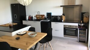 Una cocina moderna con una isla central, electrodomésticos negros y una lámpara colgante blanca y original.