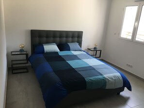 A bedroom with a large bed, two bedside tables, and a window.