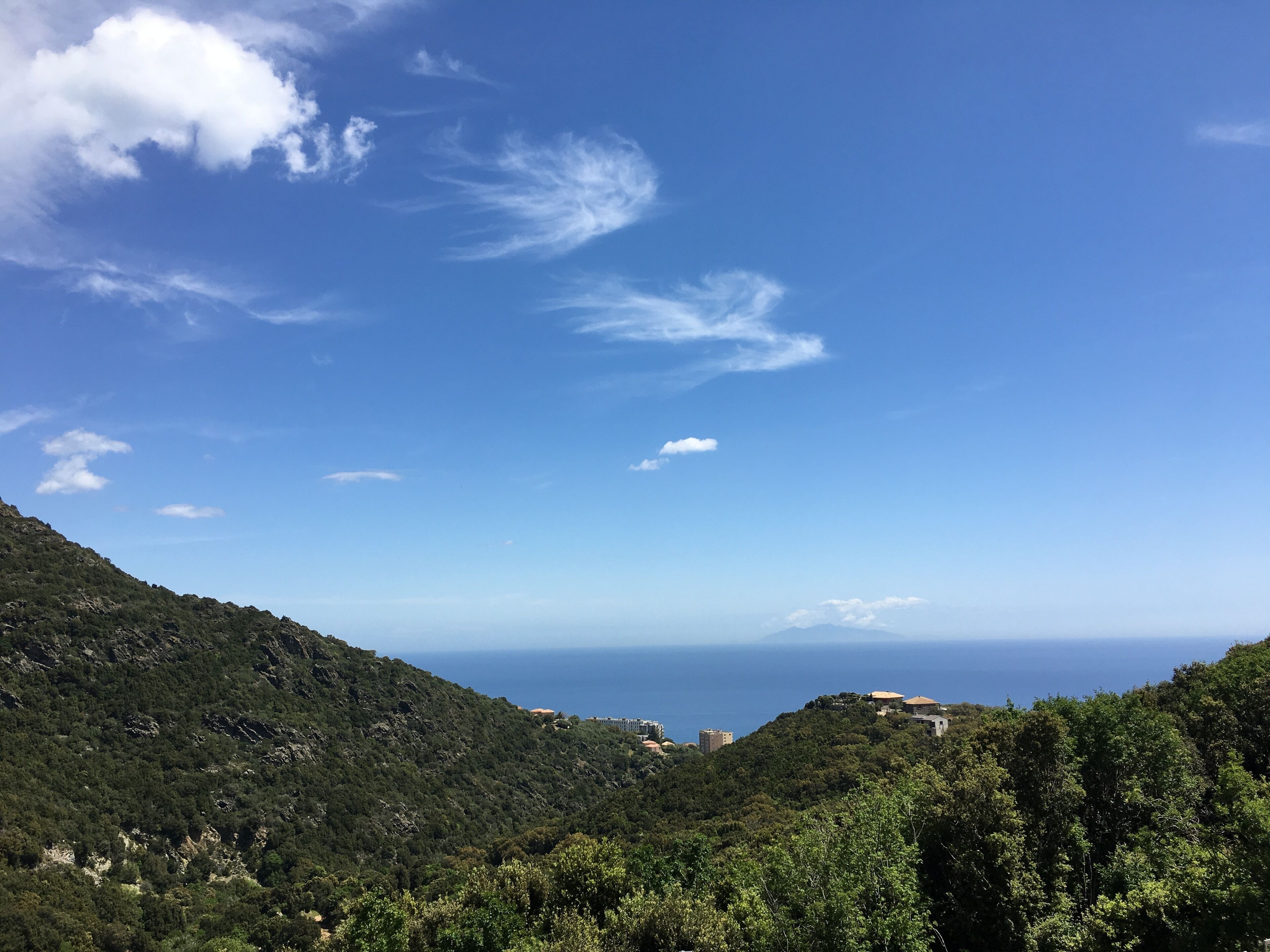 A mountainous landscape with a clear sky and a view of the sea.