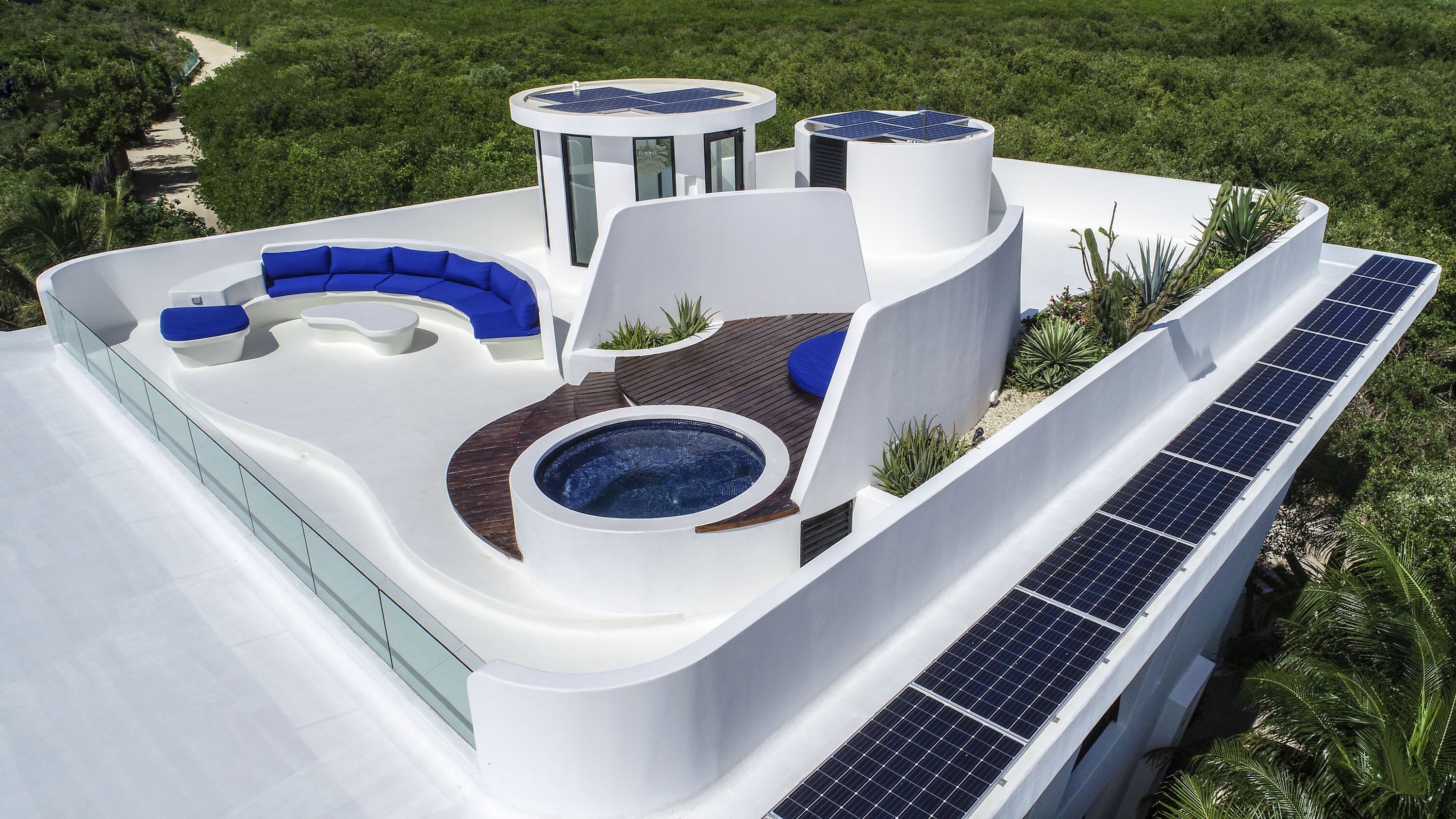 A modern rooftop with a hot tub, seating area, and solar panels.